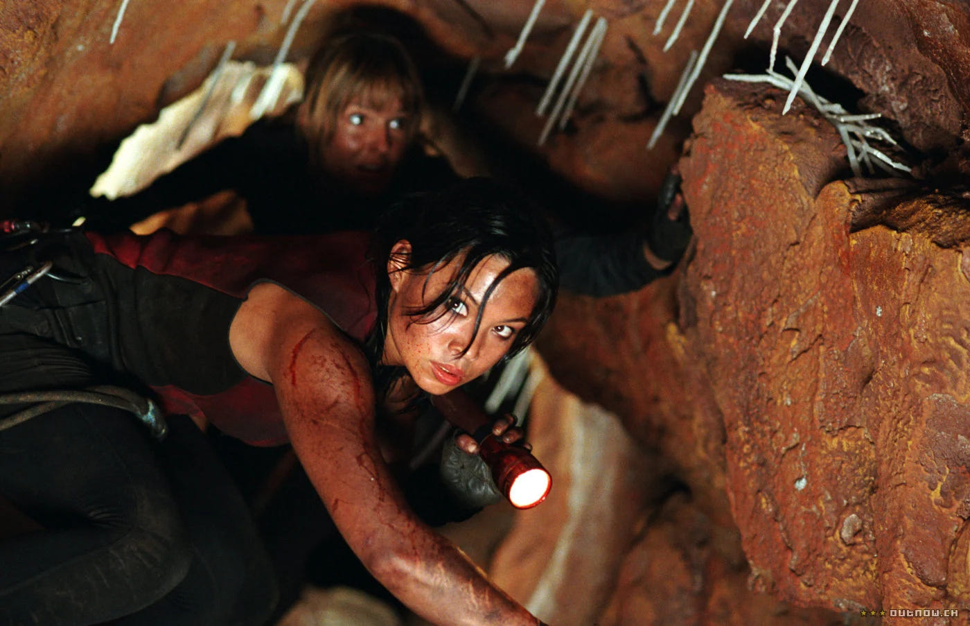 The Descent – Abgrund des Grauens – Eine Frau zwängt sich mit einer Lampe durch eine enge Höhle