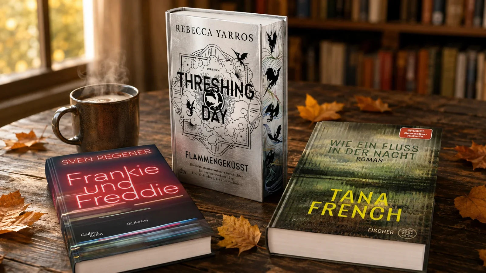 Buch-Neuerscheinungen im September auf einem Holztisch: Threshing Day von Rebecca Yarros mit Farbschnitt, Frankie und Freddie von Sven Regener und Wie ein Fluss in der Nacht von Tana French, daneben Kaffee und Herbstlaub